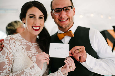 Wedding couple holding their haiku between them with big smiles